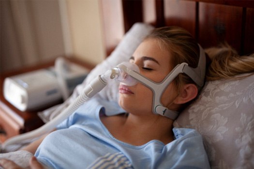 A woman wearing a CPAP mask while sleeping near Oak Ridge