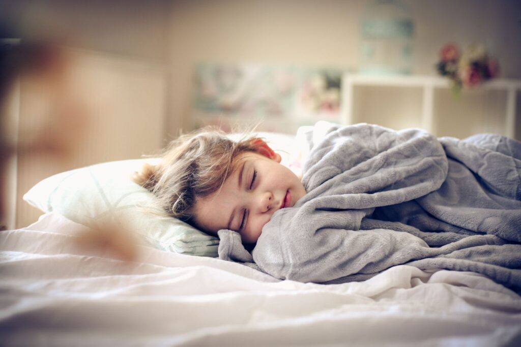 Young child in bed sleeping with gray blanket