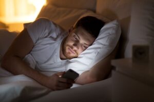 Man looking at his phone while lying in bed 