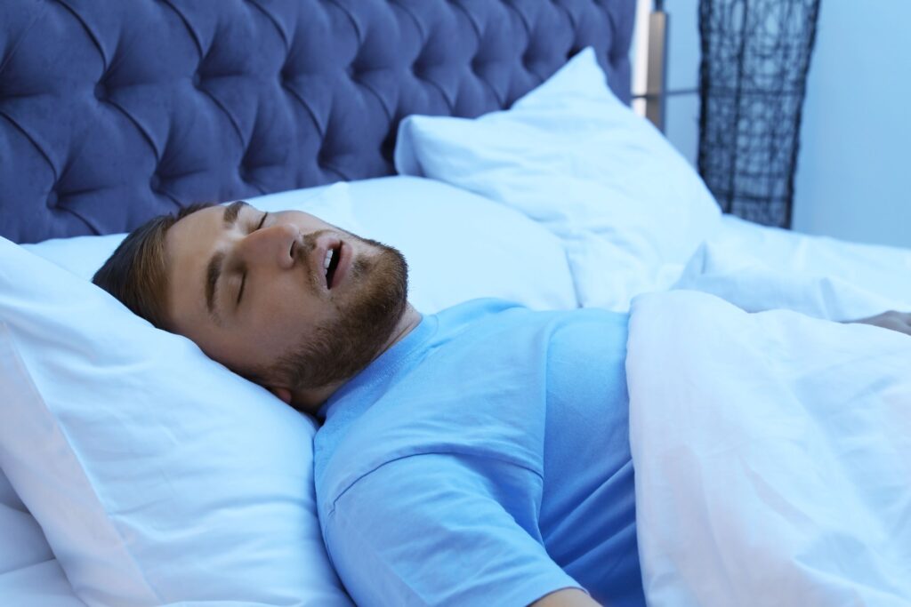 Man in blue t-shirt asleep in white bedding