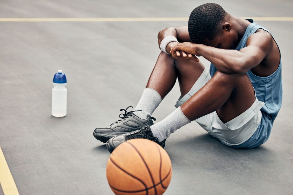 An exhausted man resting on a basketball court